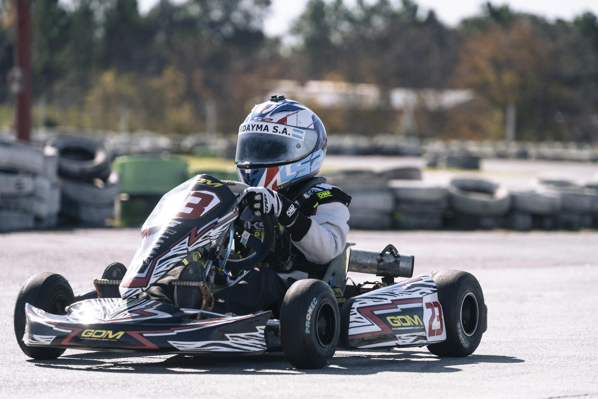 A go-kart racer in action on a sunny day at the race track, showcasing speed and skill.